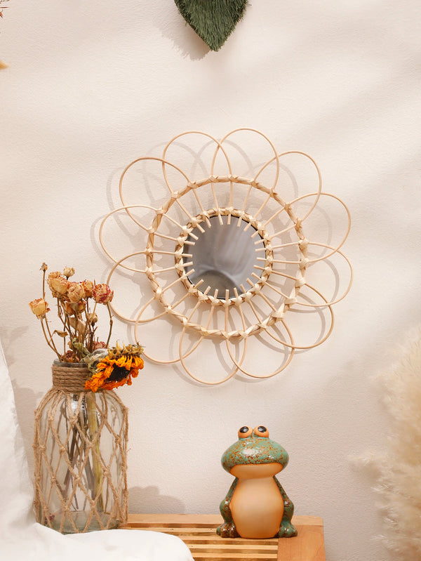 A hand woven rattan decorative wall mirror surrounded by dried flowers and natural textures.