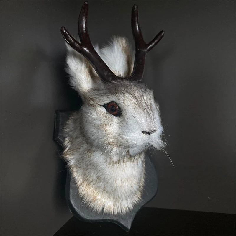 A decorative bunny head with brown antlers and white fur mounted on a dark background.