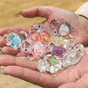 Una mano sostiene una colección de estatuas pequeñas y coloridas de tortugas marinas transparentes para decorar.