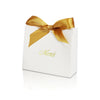A white paperboard gift box tied with a gold ribbon and the word Merci written on the top.
