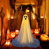 A white ghost decoration with a hood and glowing eyes is displayed in a dimly lit, rustic interior setting.
