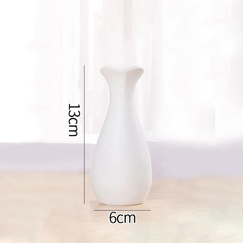 A white ceramic bud vase with a slender neck and rounded body is shown against a light background.