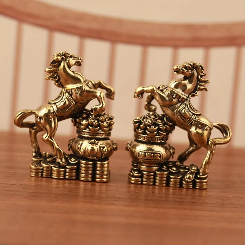 A pair of solid copper horse figurines for prosperity and positive energy, displayed on a wooden surface.