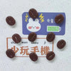 A set of dark brown coffee beans displayed on a purple fridge magnet with a white rabbit design and a 100% symbol.