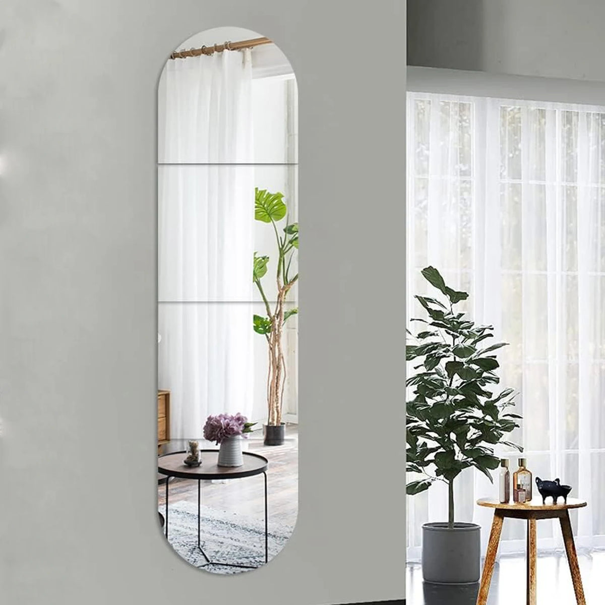 A vertical acrylic mirror wall sticker featuring a white curtain and a potted green plant on a gray wall.