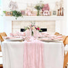 A white table set with pink and floral accents, featuring a light blue cheesecloth table runner for rustic events.