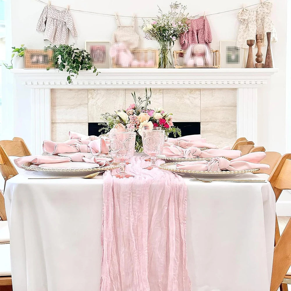 A white table set with pink and floral accents, featuring a light blue cheesecloth table runner for rustic events.