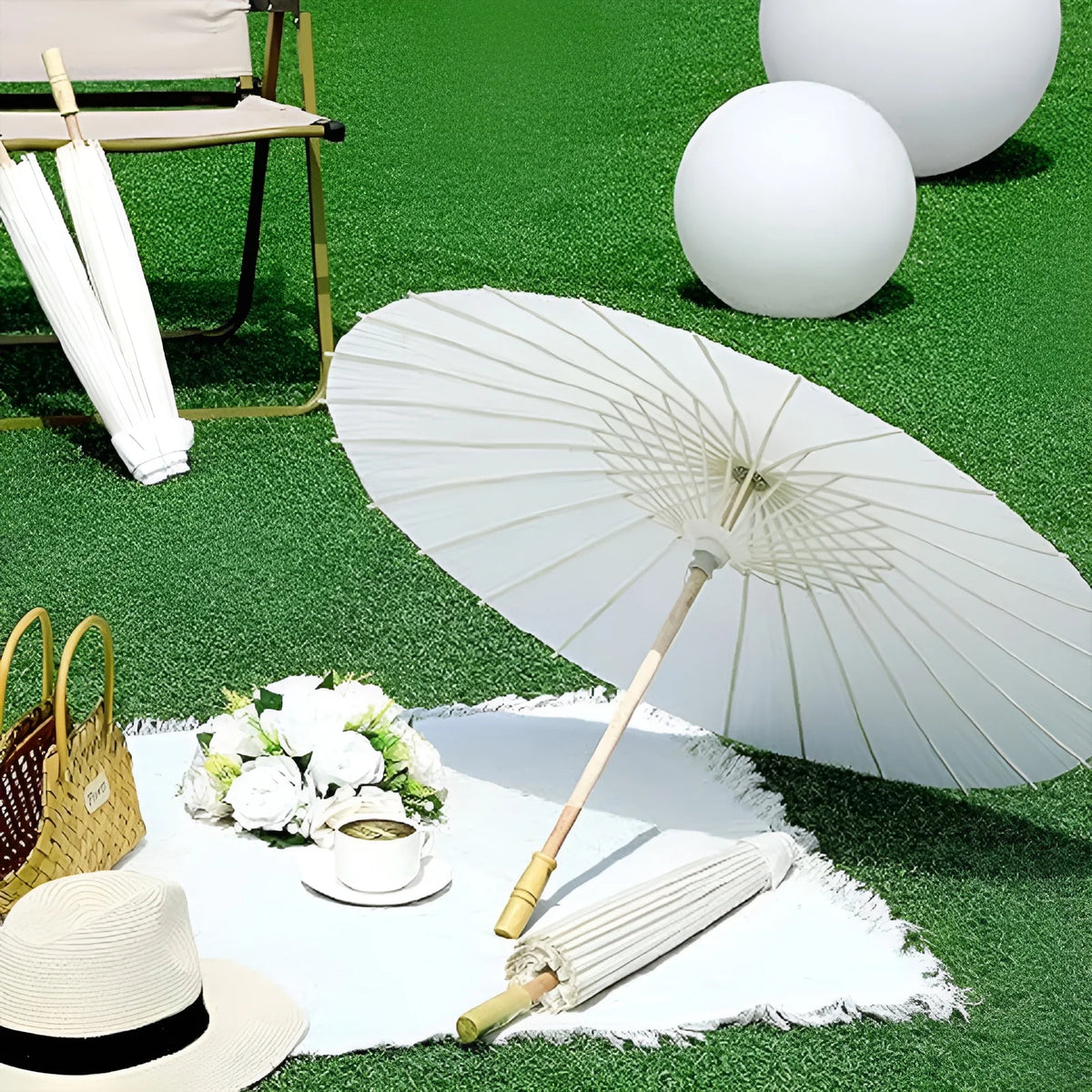 A white oil paper umbrella is shown open on a green surface with white flowers and a cup.