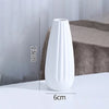 A white ceramic bud vase with vertical ridges is shown on a surface, with dimensions marked.