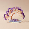 A natural amethyst crystal tree with branches on an agate base used as a feng shui money tree for home decor