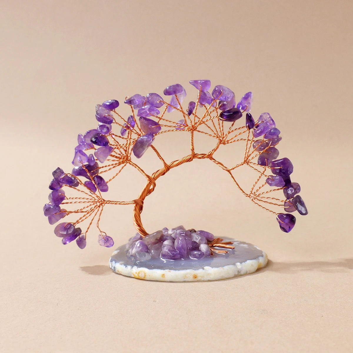 A natural amethyst crystal tree with branches on an agate base used as a feng shui money tree for home decor