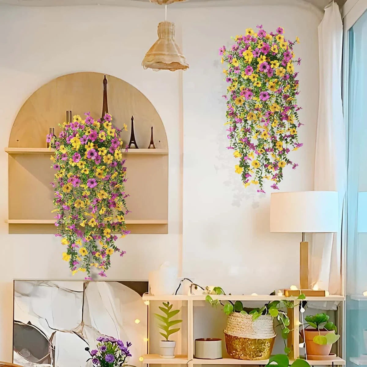 A display of vibrant faux silk flowers in yellow and purple cascading down a white wall.