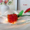 A glowing orange rose flower made from building blocks is displayed on white fabric.