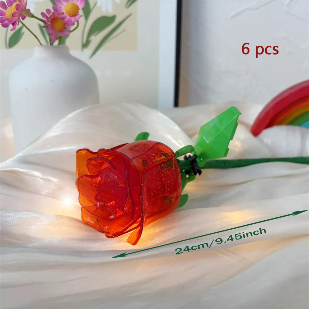 A glowing orange rose flower made from building blocks is displayed on white fabric.