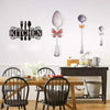 A black metal wall art sign featuring a kitchen silhouette and an orange butterfly design on a white wall.