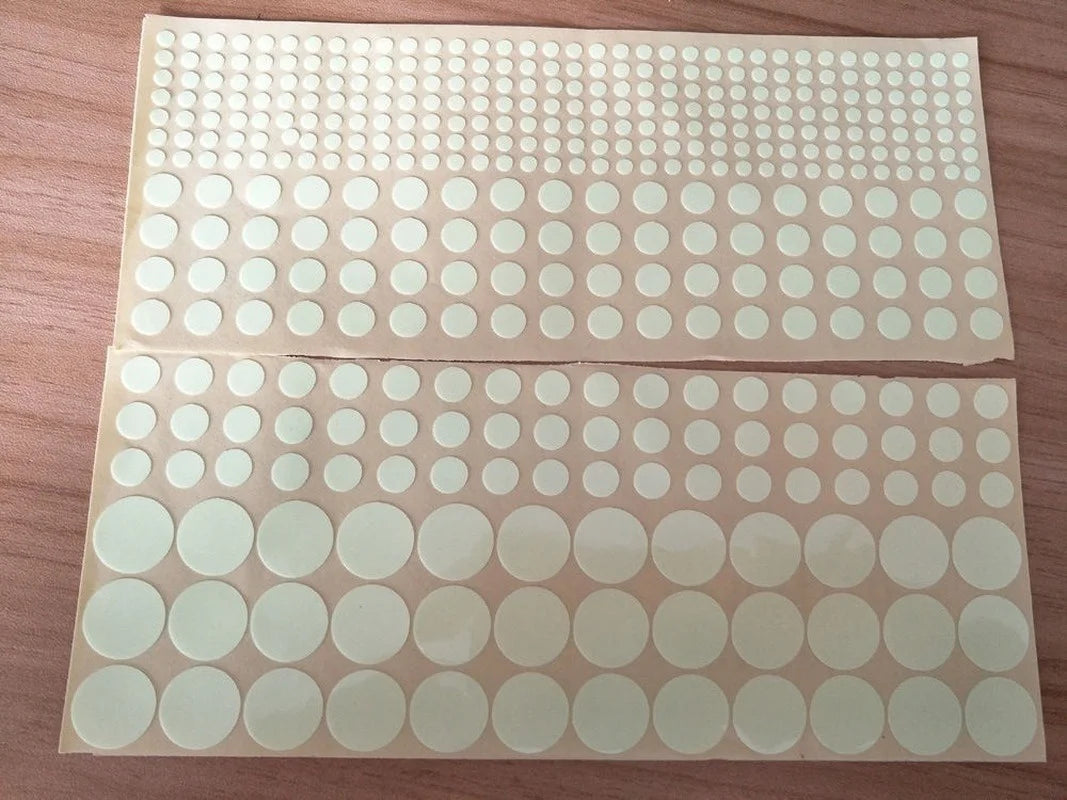 A sheet of glow-in-the-dark star wall stickers for kids, featuring various sized white circles on a translucent background.