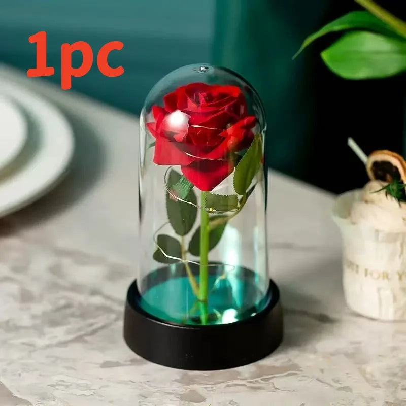 Ein Glasvase mit roter Rose und grünem Stiel wird von einer LED-Lampe beleuchtet, auf einer schwarzen Basis platziert.