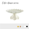 White plastic cake stand with a scalloped edge shown against a white background.