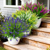 A vibrant display of artificial lavender and yellow flowers in white pots arranged on wooden steps.