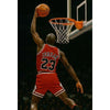 A basketball player in a red jersey and shorts is dunking or shooting a ball through a hoop.