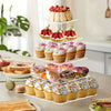 A tiered transparent acrylic cupcake stand filled with various frosted cupcakes and fresh strawberries.