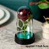 An artificial deep red rose is displayed inside a glass dome on a black base.