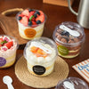 A collection of reusable pudding cups filled with fruit and cream, set on a wooden surface.