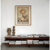 A framed mystical tarot poster featuring a sun-like face and the text The Dreamer hanging on a white wall above a wooden shel