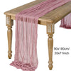 A long, sheer mauve gauze fabric draped over a wooden table.