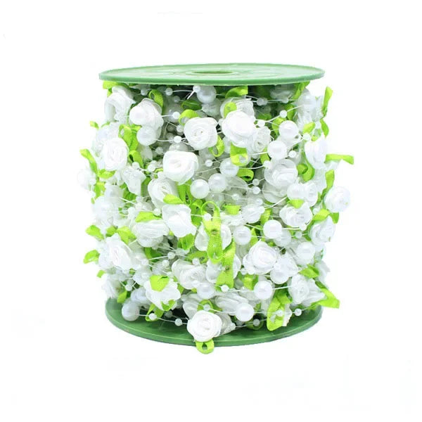 A cylindrical arrangement of white roses and green leaves used as a floral garland or ribbon.