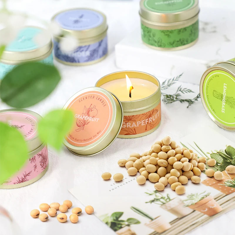 A collection of natural soy wax travel candles in various colors and jars, surrounded by dried ingredients like peppercorns a