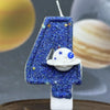 A blue glitter number four candle decorated with stars and a white planet design.