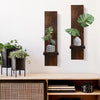 Vintage wooden wall candle holders displaying potted green plants on a white wall.