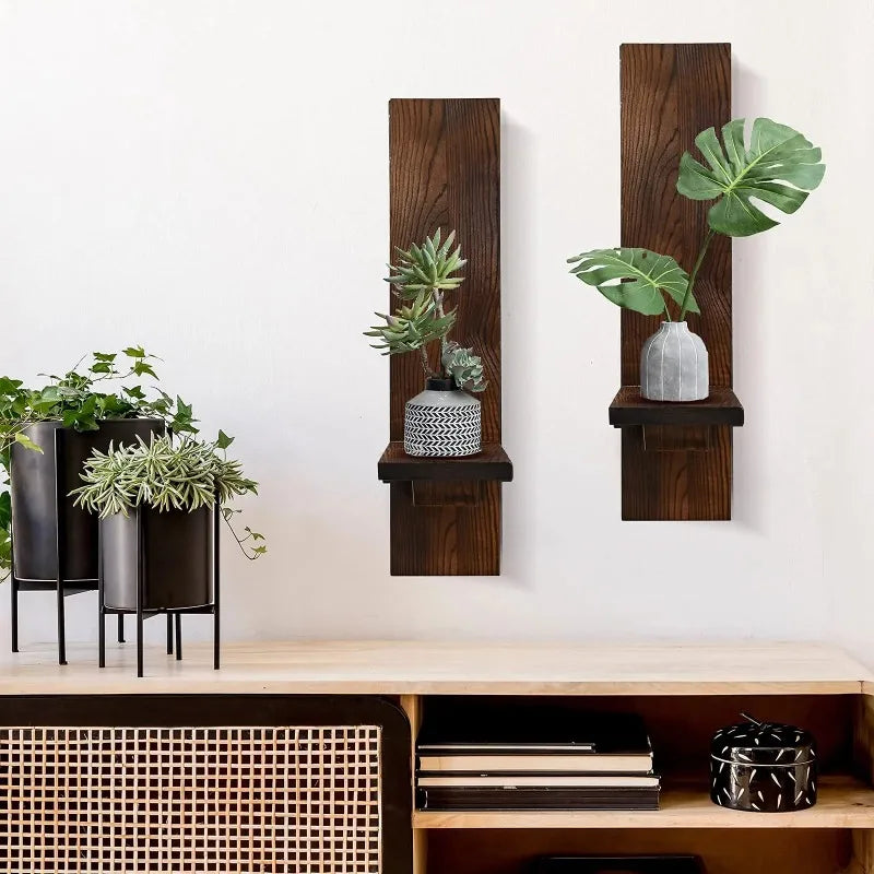 Vintage wooden wall candle holders displaying potted green plants on a white wall.