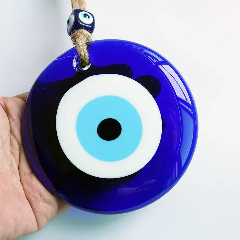 Une main tient un ornement en verre rond bleu avec un œil de nouveau blanc et bleu sur fond bleu foncé.