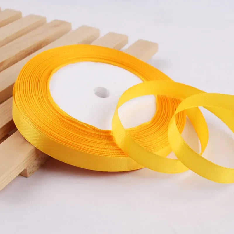 Roll of gold yellow satin ribbon on a wooden surface for crafts and gift wrapping