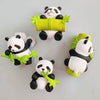 Three adorable panda figurines holding a yellow leaf-shaped object, used as fridge magnets.