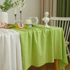 A lime green cotton rectangle tablecloth is set for dining with white flowers and decorative elements.