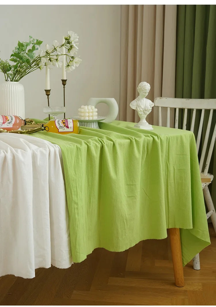 A lime green cotton rectangle tablecloth is set for dining with white flowers and decorative elements.