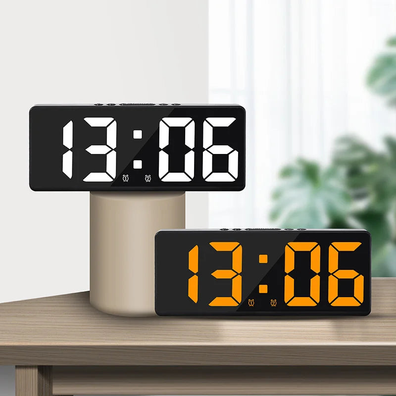 A black LED digital alarm clock displaying 13:06 on a wooden surface.