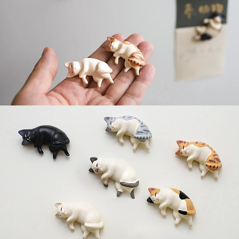 A collection of six white and orange cat figurines used as fridge magnets, displayed on a white surface.
