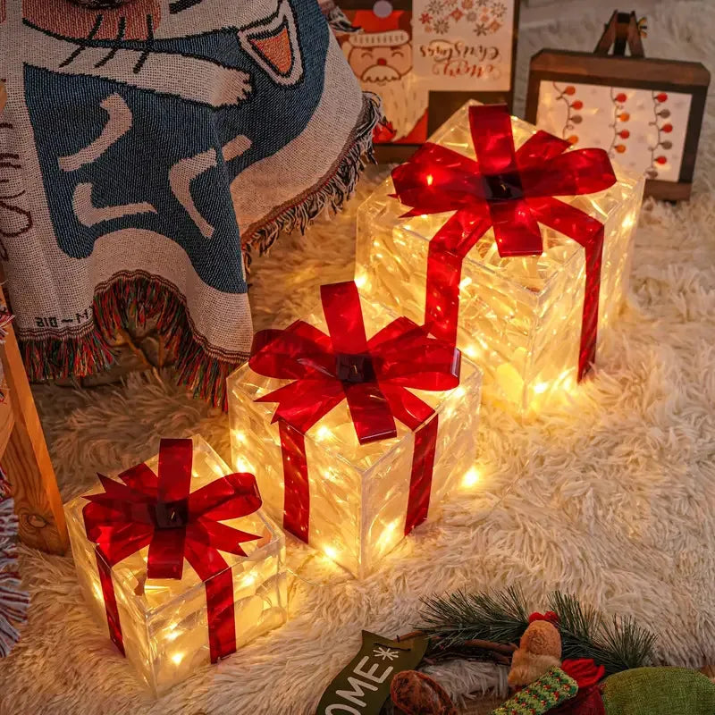 A set of three red LED light-up Christmas gift boxes resting on a fluffy white rug.