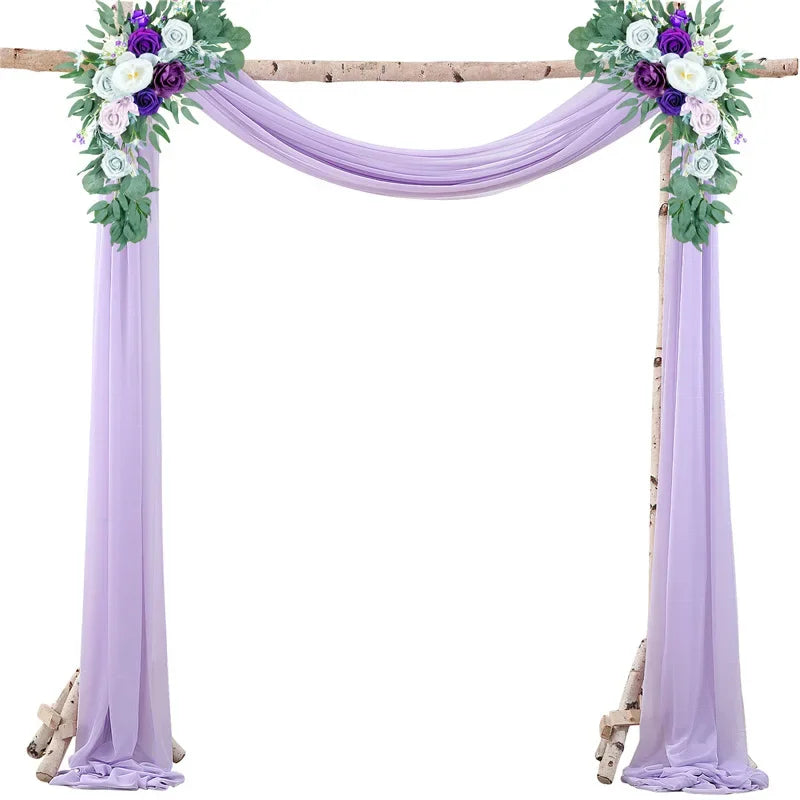 A purple chiffon wedding arch with floral greenery and purple accents draped over a wooden frame.