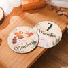 A set of seven newborn milestone cards featuring a number and the word months, displayed on a wooden surface.