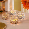 A set of crystal tealight candle holders with metal bases arranged on a light surface.