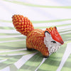 Hand-painted resin fox totem statue with orange textured head and white fur on a green striped background.