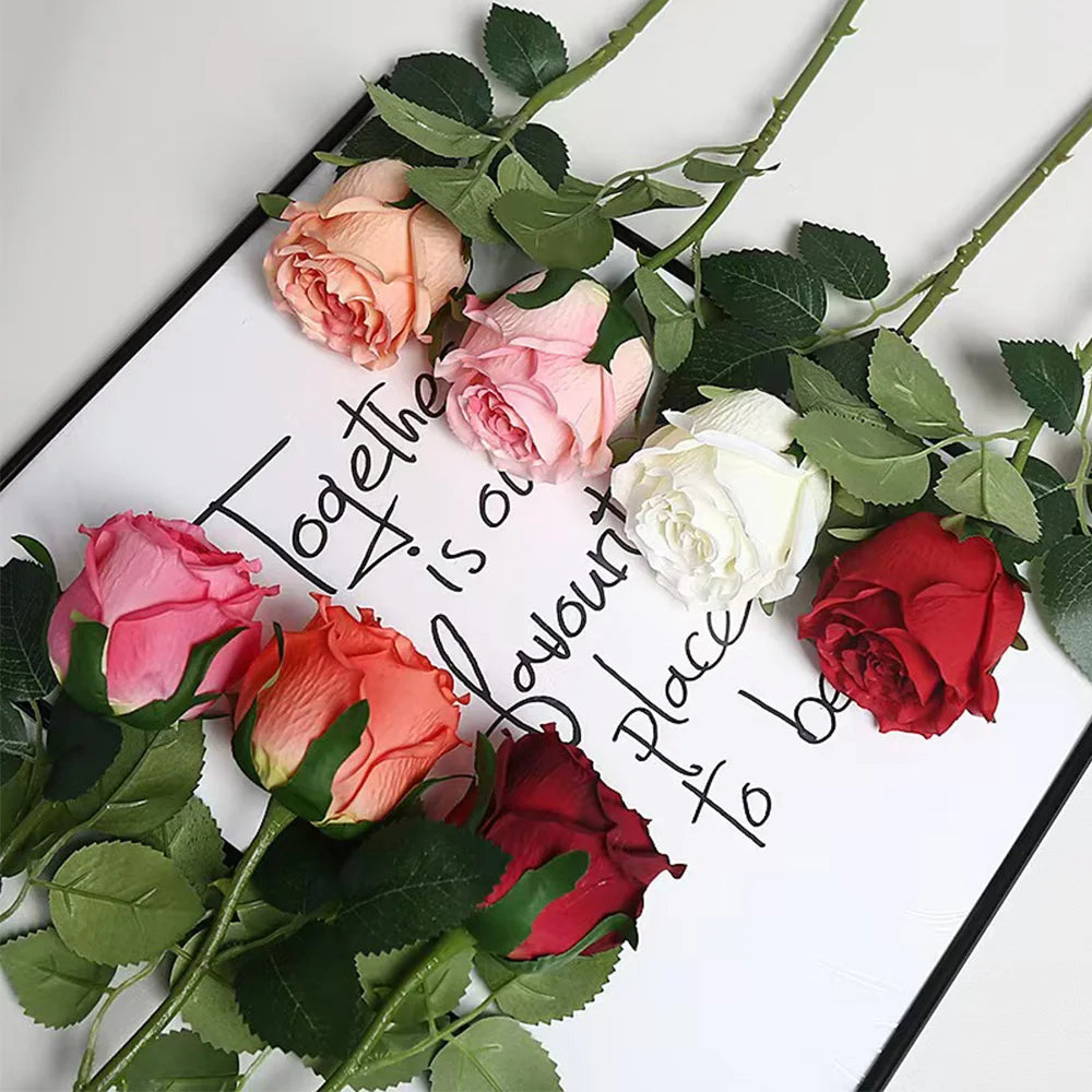 A bouquet of artificial roses in shades of pink, red, and white arranged on a white card.