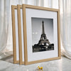 A set of three light wood photo frames displaying a black and white image of the Eiffel Tower.