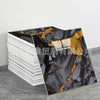 A roll of faux marble 3D self-adhesive wall tiles featuring black and gold veining displayed on a gray surface.