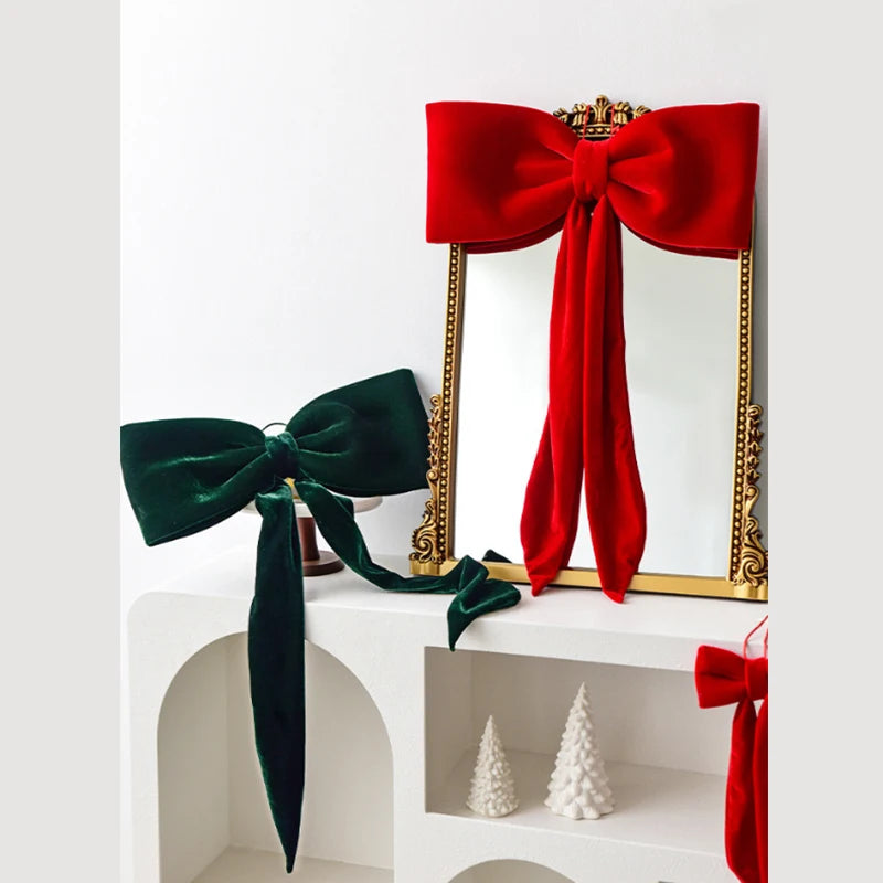A set of twelve velvet Christmas tree bow ornaments in red and green displayed on a white shelf.
